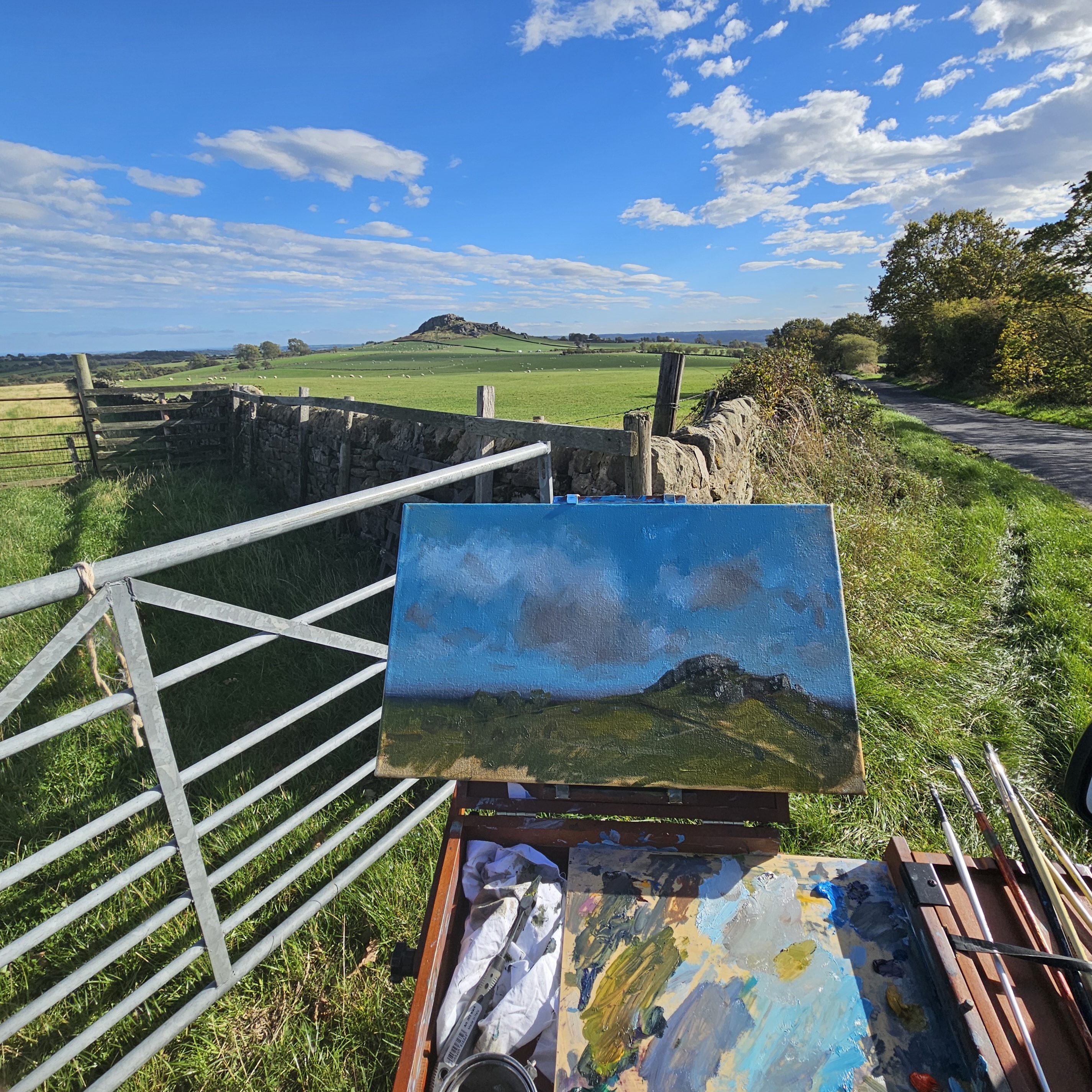 Easel set up on a gate overlooking Almscliffe Crag, Yorkshire, with the rock outcrop visible in the distance