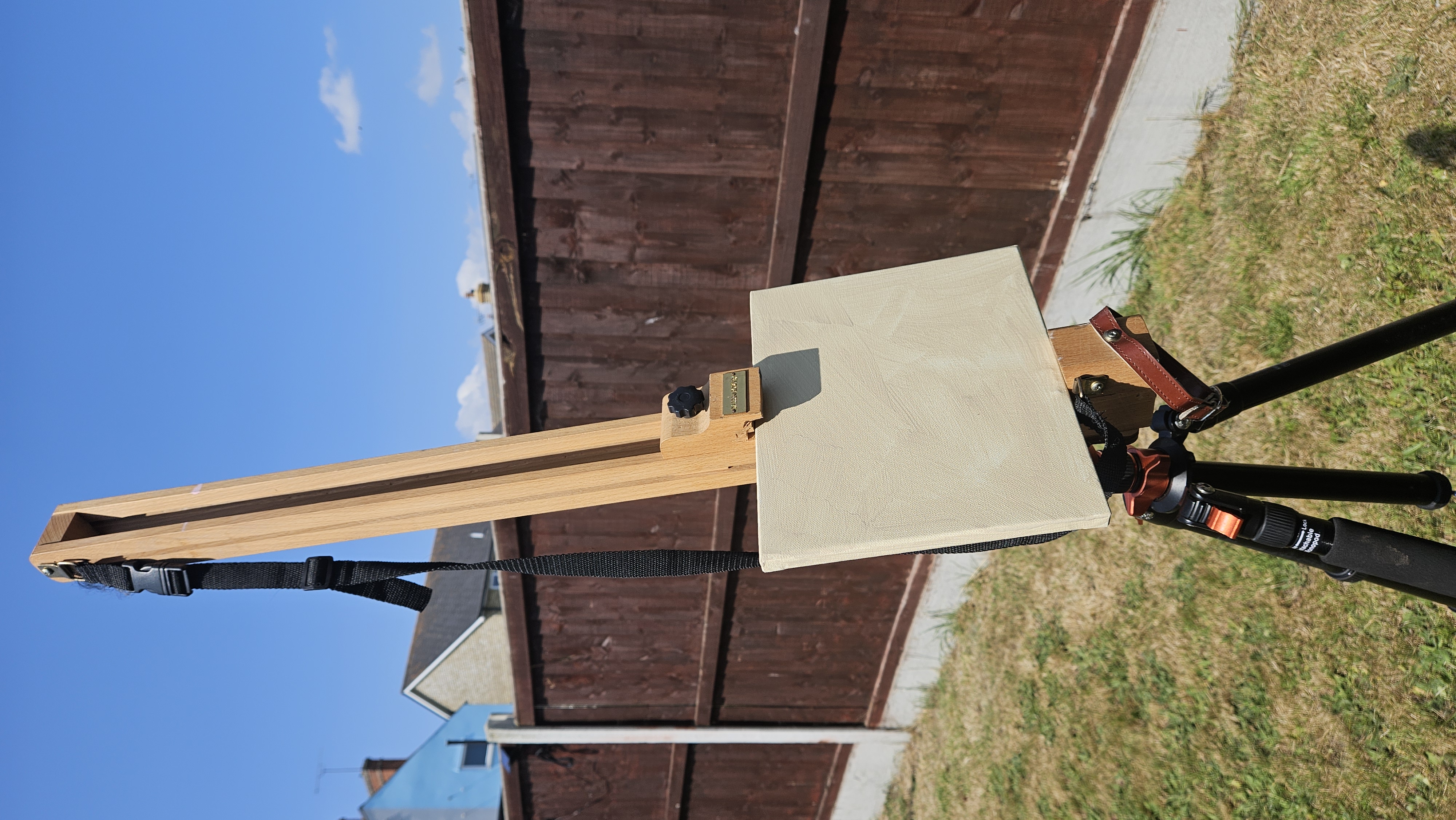 A blank primed canvas set up on a portable easel outdoors, testing a plein air setup
