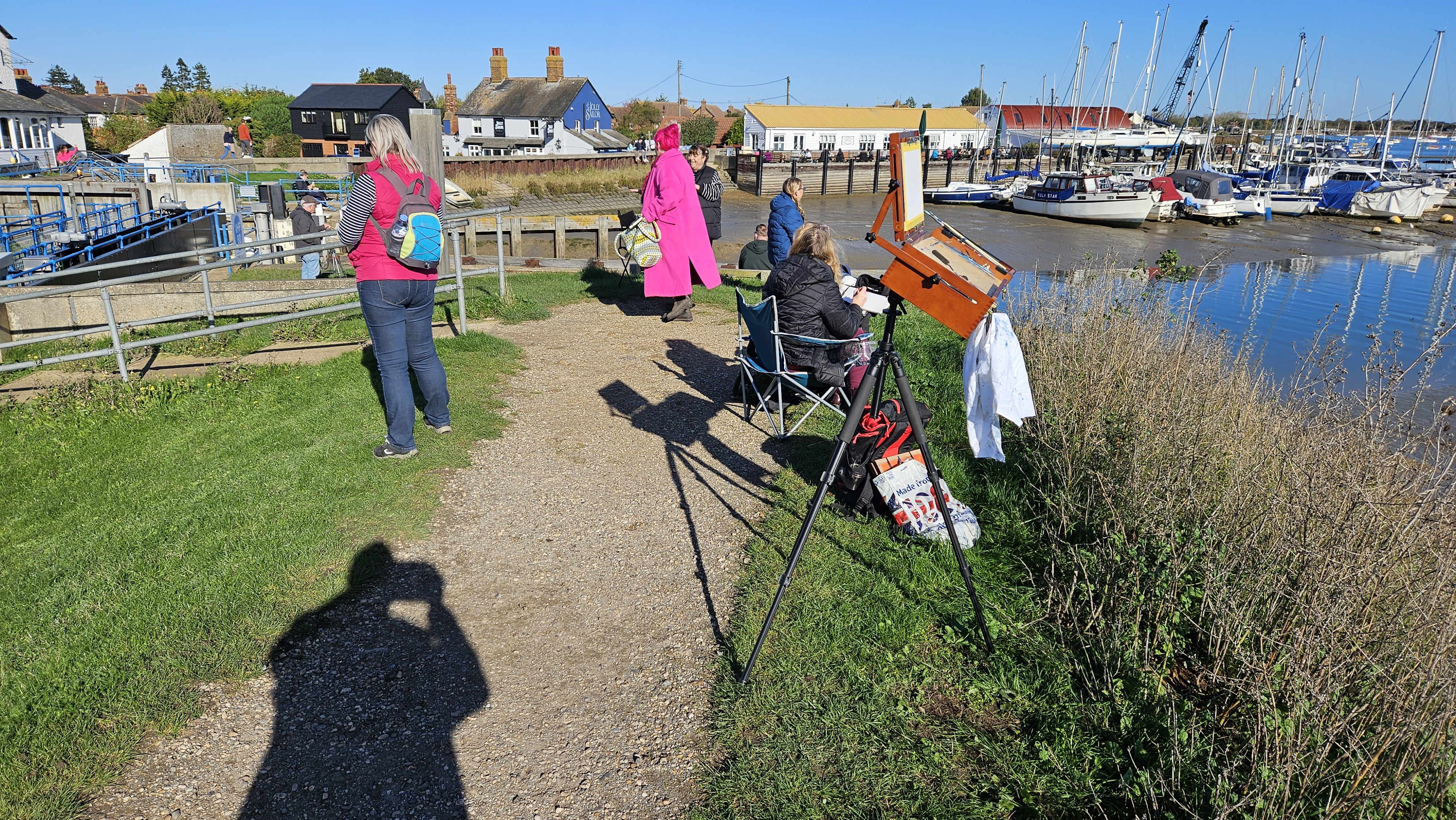 Lawrie Flood painting en plein air at a harbourside, easel set up looking out over the water and moored boats